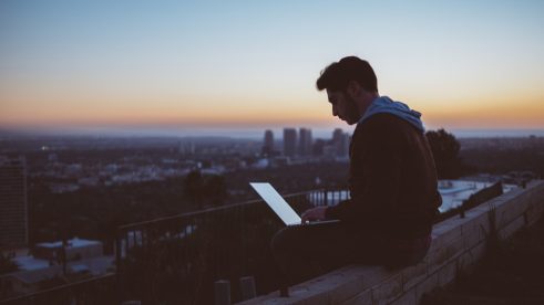 using a laptop over a sunset cityscape
